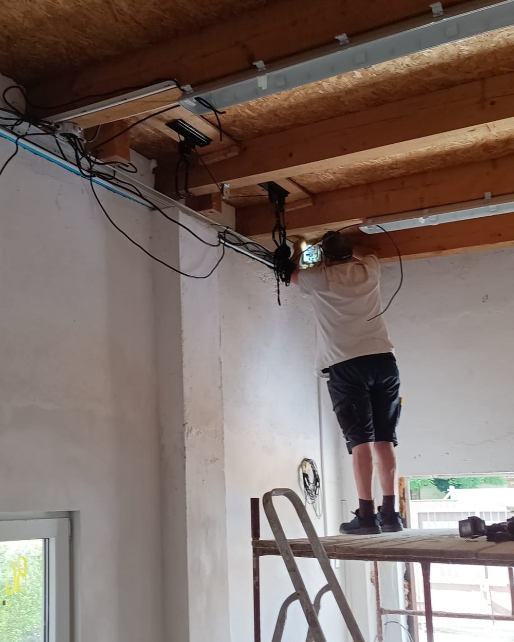 Radek Hořejší při montáži elektroinstalace pod stropními trámy